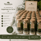 A promotional display of MossBoss DIY gift sets for hosts, featuring multiple small glass jars with cork lids filled with green moss, white pebbles, and decorative elements, alongside a larger branded sign and informational text in Bulgarian.