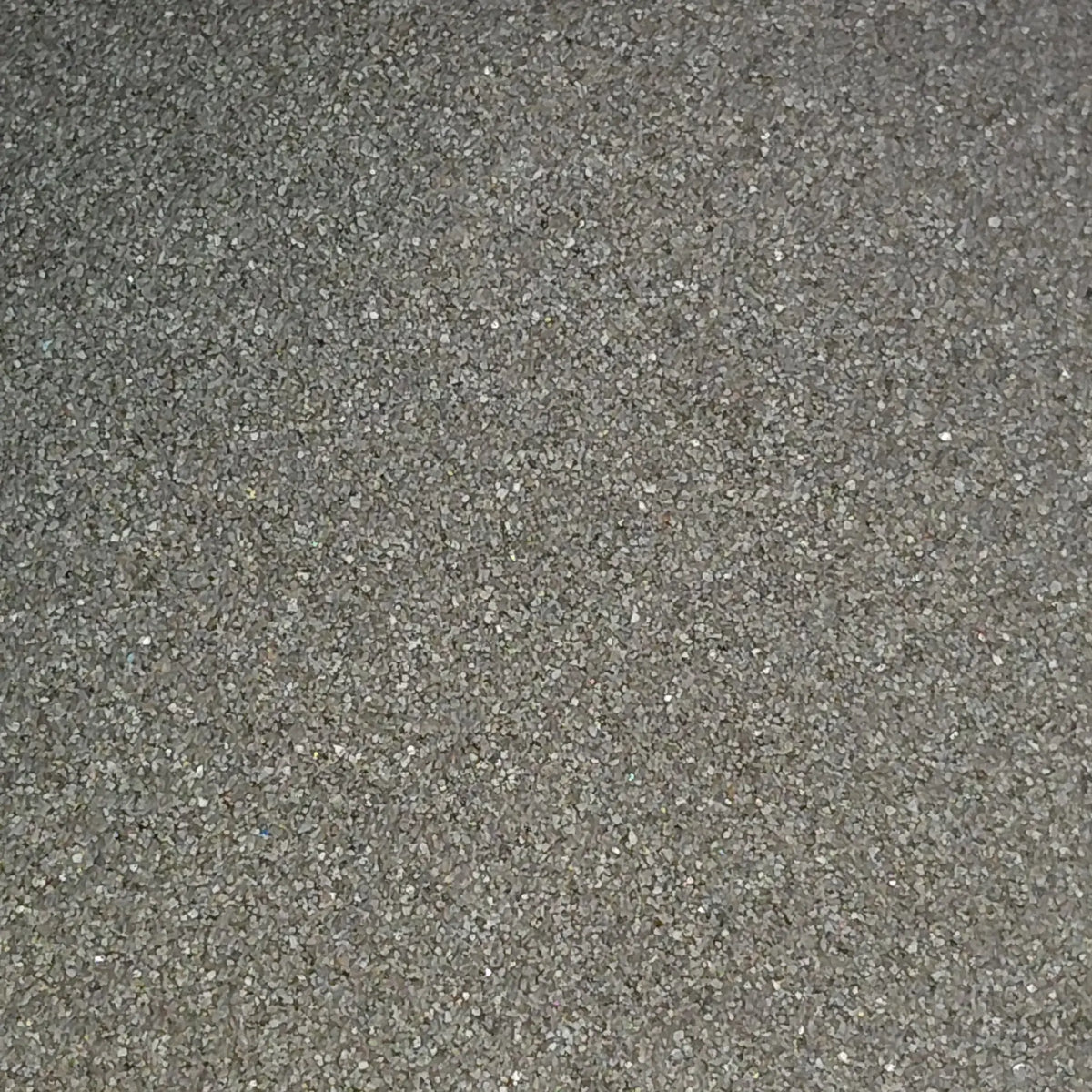 Close-up of dark gray sand or powder on a light background